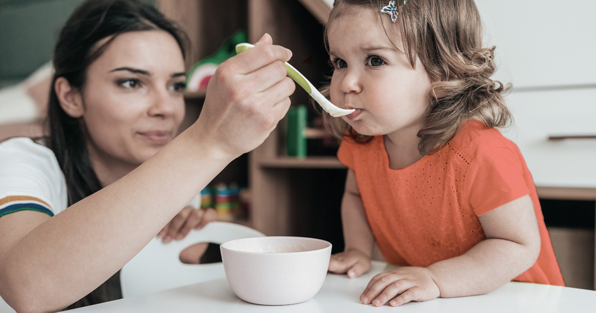 An adult feeding a child with a spoon.