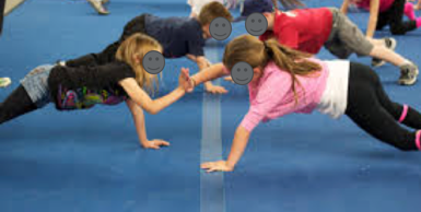 Children in a plank position facing one another to slap hands is an example of a motor planning task.