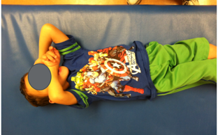 A young boy lying on a therapy table in the range of motion assessment position