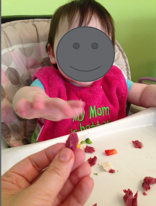 A parent offering a finger food to child