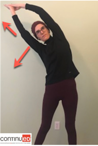 Photo of a young woman standing to demonstrate a whole body stretch with a lean to the right