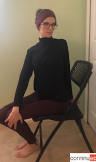 Photo of a young woman sitting in a folding chair and performing a seated twist yoga pose