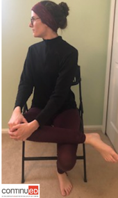 Photo of a young woman sitting in a folding chair and performing a seated pigeon yoga pose