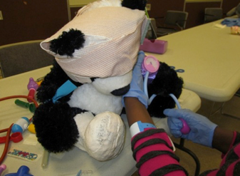 Child reenacting a medical procedure using a teddy bear