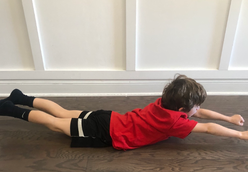 Testing for the Landau reflex with child in prone with the child lifting legs off the ground showing possible reflex retention