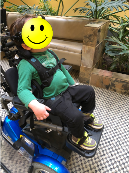 Boy sitting in a blue wheelchair with all of the primary support surfaces on a wheelchair