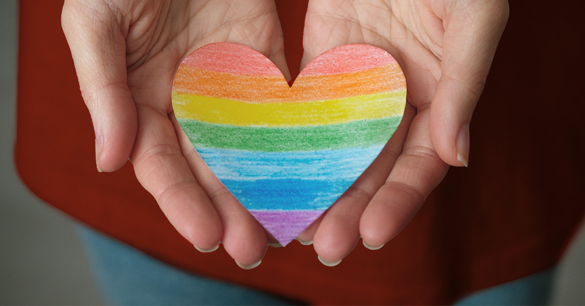 Hands holding a rainbow heart