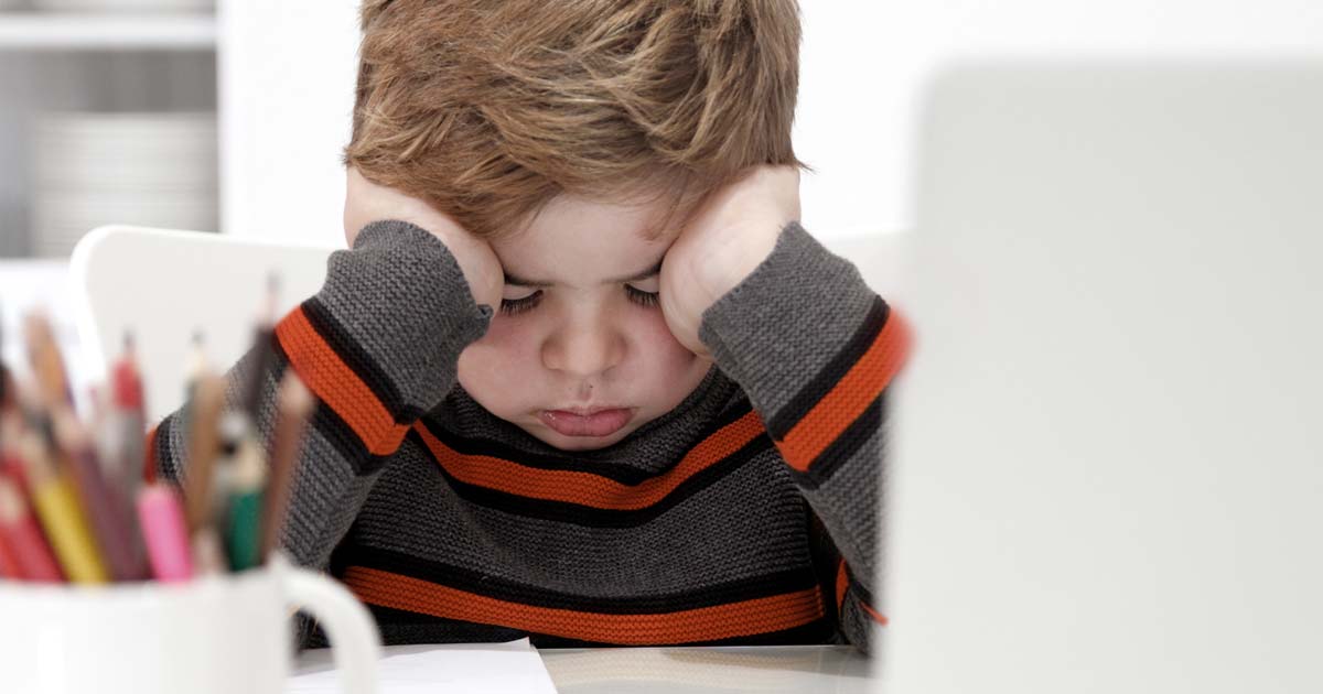 A young child sitting with their head between their hands 